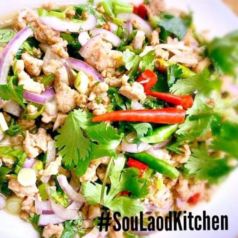 Grilled skewered meat on a plate with sticky rice in a woven basket and a side of sauce.